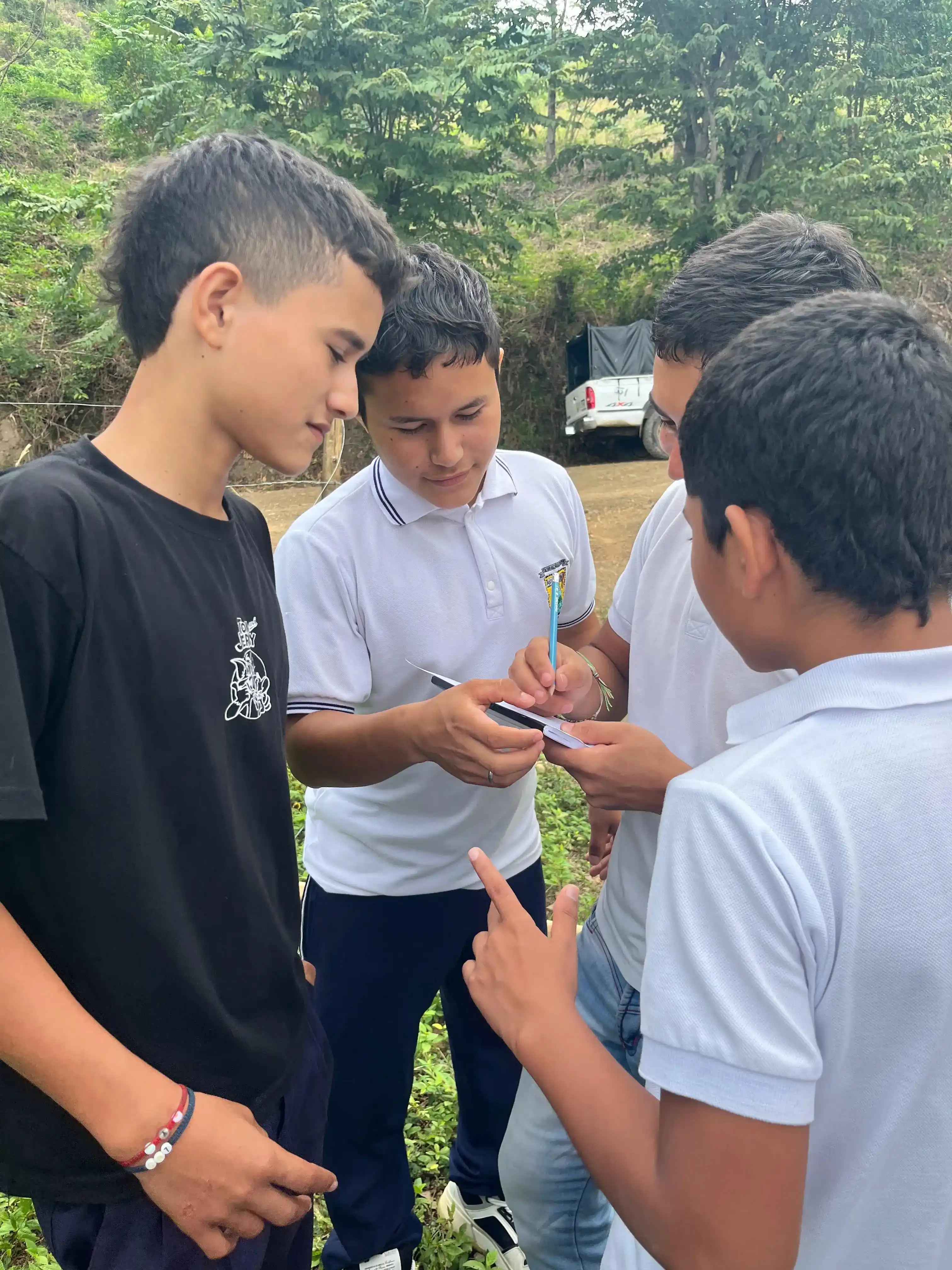 Estudiantes reunidos al aire libre tomando notas en bitácora durante la salida de campo