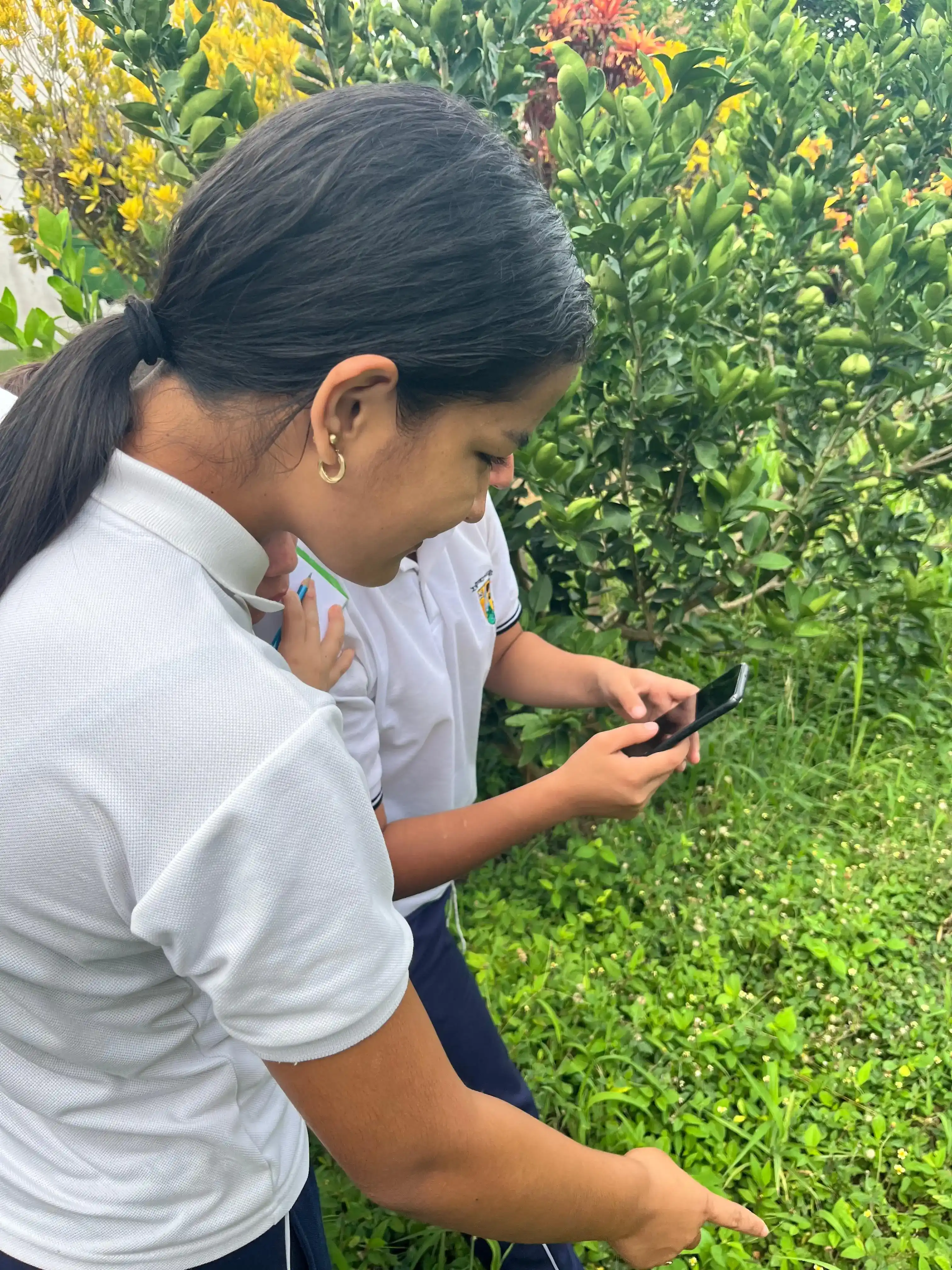 Dos estudiantes observan y fotografían plantas en el entorno de la sede Boquerón
